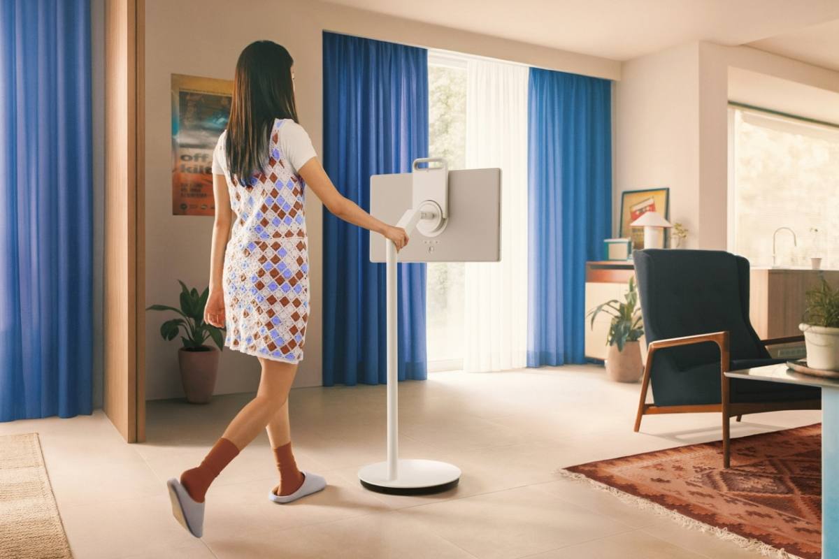 Samsung The Movingstyle - žena postavlja TV na prijenosnom postolju u sobi